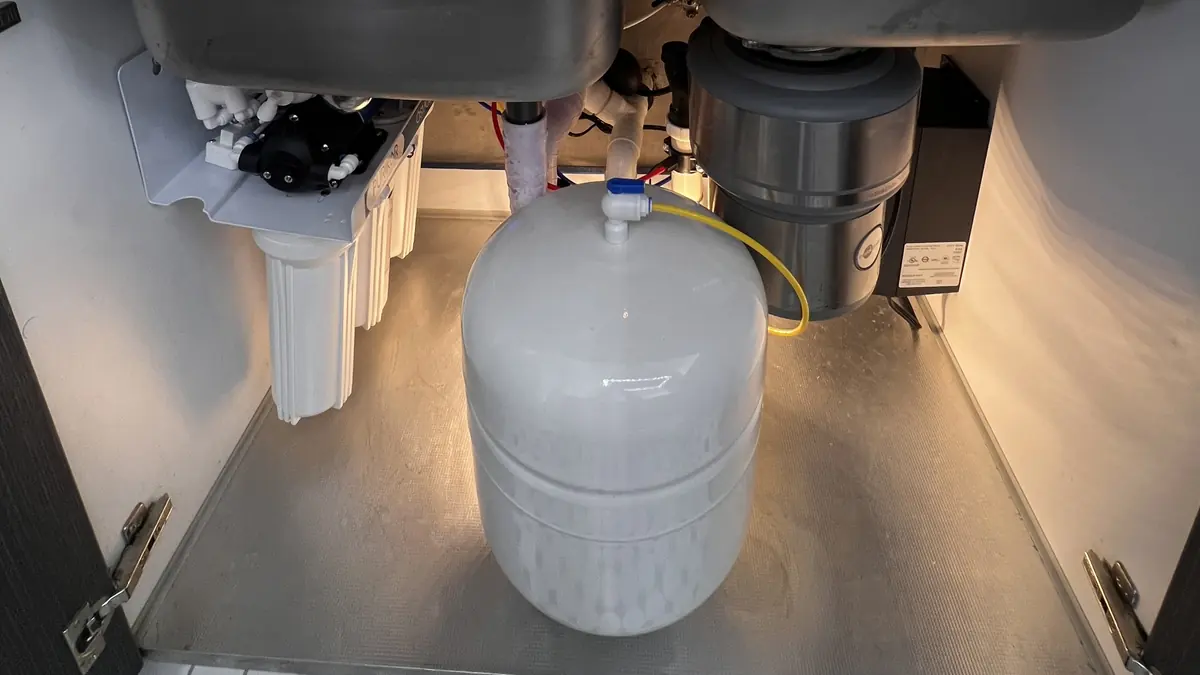 Purikor 6-Stage reverse osmosis system installed under a kitchen sink, with the storage tank on the cabinet floor